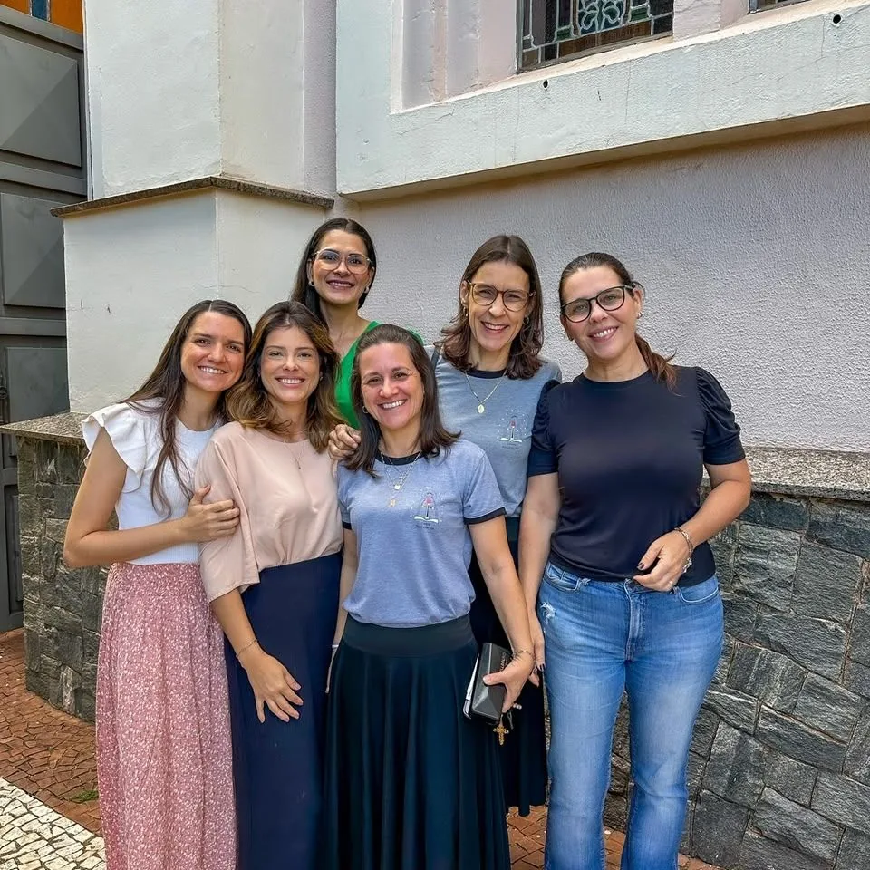 Seis mulheres reunidas diante de uma igreja