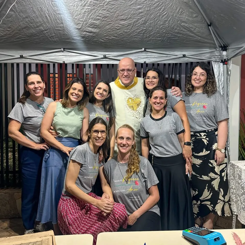 Grupo reunido sob uma cobertura, com um sacerdote ao centro