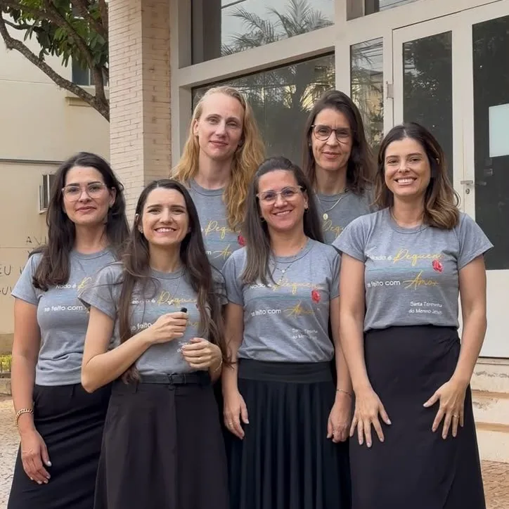Cinco mulheres reunidas em frente a um prédio
