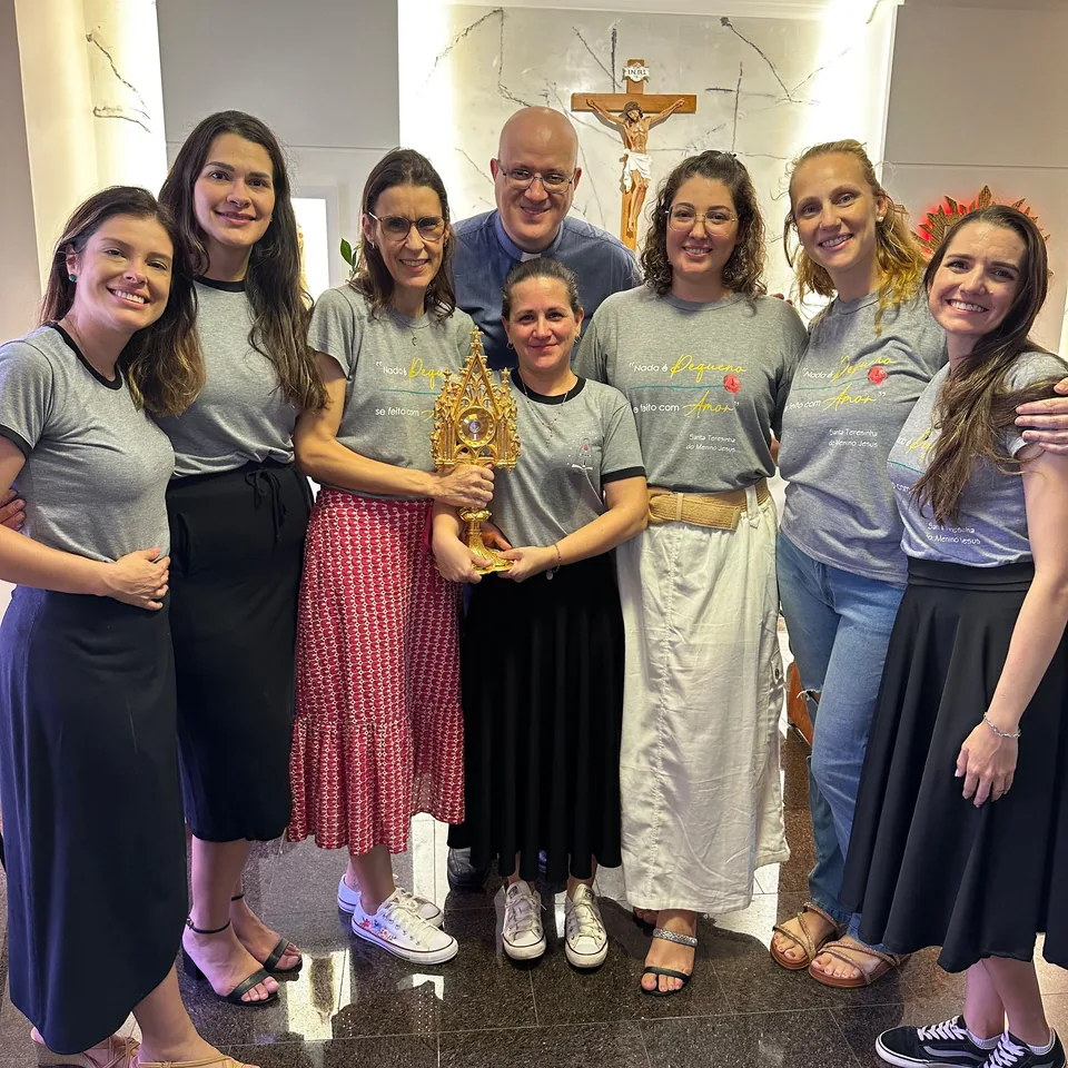 Grupo reunido na capela com um sacerdote e um relicário