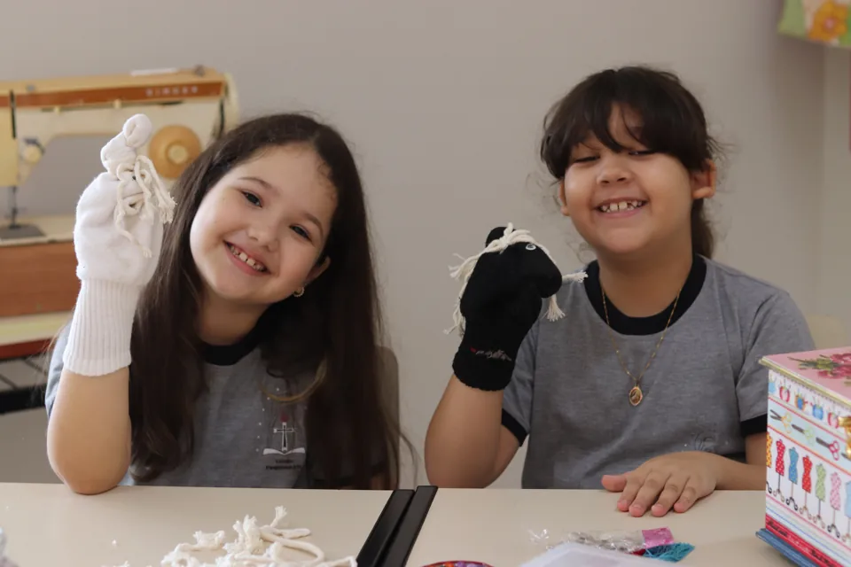 Alunas mostrando bonecos feitos com meias