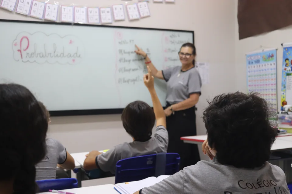 Cena de aula com uma adulta diante da lousa