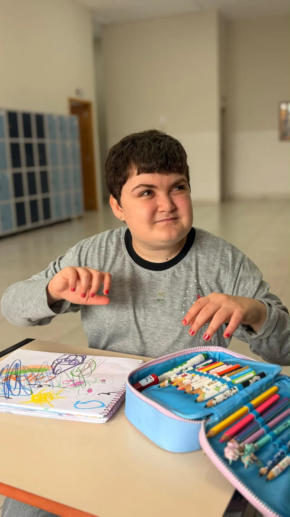 Aluna do Colégio Pequena Via em atividade de desenho, com caderno e lápis de cor